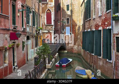 Bateaux sur le canal étroit parmi les vieilles maisons typiques avec des murs de briques rouges à Venise, Italie Banque D'Images