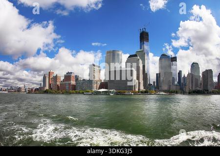 Une photo d'un ferry regardant en arrière sur Manhattan skyline. L'eau montre la trace laissée par le ferry Banque D'Images
