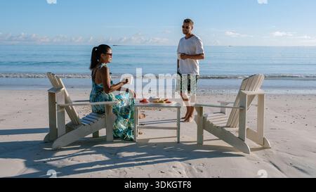 Deux personnes profitent d'une matinée paisible à Grand Anse Beach, Praslin Seychelles, partageant boissons et fruits tout en profitant de la vue imprenable sur l'océan Banque D'Images
