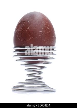 Dark brown soft oeuf dur avec brisé la coquille dans une spirale se tenir sur fond blanc Banque D'Images