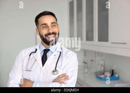 Médecin souriant confiant posant les bras croisés regardant à distance Banque D'Images