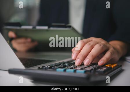 Comptable main utilisant la calculatrice finance d'entreprise, calcul de l'impôt, planification budgétaire, analyse financière des documents sur presse-papiers, travailler au bureau d Banque D'Images