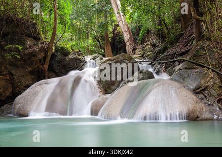 Chutes d'Erawan cascades d'eau dans la jungle luxuriante du parc national d'Erawan, Thaïlande. L'eau bleue claire coule sur des roches lisses. Banque D'Images