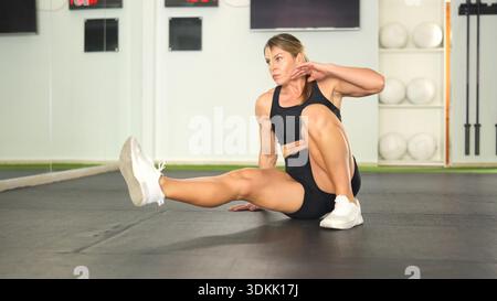 Femme exerçant la force de base faisant l'entraînement de fitness dans le gymnase Banque D'Images