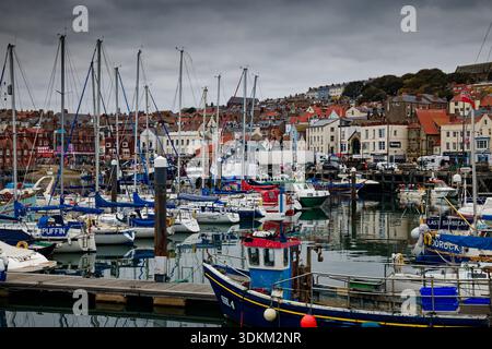 Un port animé plein de yachts amarrés avec le front de mer de la ville et le port en arrière-plan, Scarborough, North Yorkshire. Banque D'Images