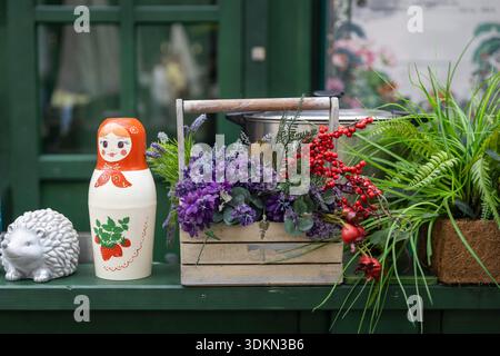 Exposition décorative de natures mortes sur étagère peinte en vert à Moscou avec poupée matryoshka russe, figurine de hérisson en céramique blanche, crate en bois Banque D'Images