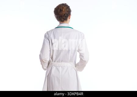 Vue arrière d'une personne portant un manteau de médecin blanc avec un stéthoscope autour du cou et les mains dans les poches, debout sur un fond blanc propre. Banque D'Images