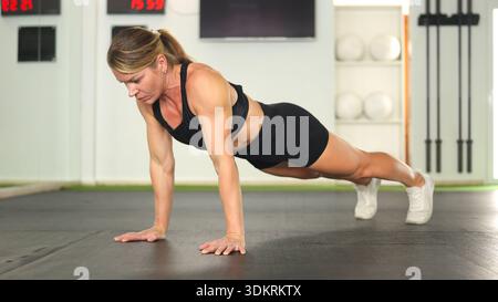 Femme exerçant faire des pompes sur le sol de la salle de gym Banque D'Images