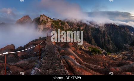 Paysage de lever de soleil en montagne sur les nuages de l'île de Madère sur Pico do Arieiro sur les falaises abruptes et les hauts sommets avec la brume matinale encore couvert Banque D'Images