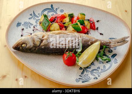 bar frit sur une assiette avec des légumes Banque D'Images