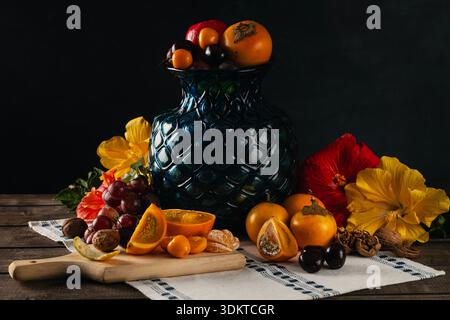 Nature morte sombre avec des fruits frais et des fleurs Banque D'Images
