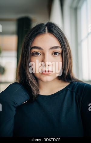 Jeune femme en haut noir regardant sérieusement dans la lumière naturelle Banque D'Images