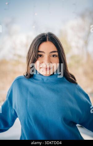 Jeune femme souriant dans le portrait extérieur bleu à col roulé Banque D'Images