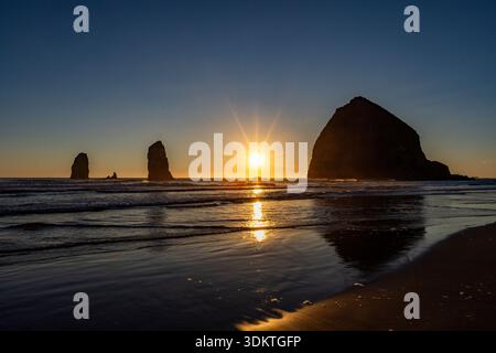 États-Unis, Oregon, coucher de soleil derrière le rocher de meule de foin sur Cannon Beach Banque D'Images