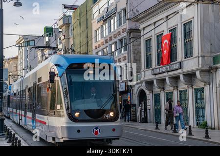 Istanbul, Turquie - 31 octobre 2025 : un tramway bleu moderne passe devant le bâtiment de la Fondation de la littérature turque dans le quartier de Sultanahmet. Banque D'Images