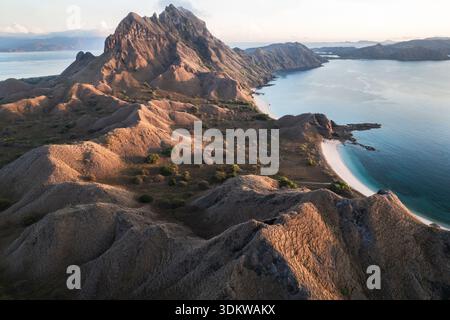 Vue aérienne des collines escarpées et baignées de soleil en cascade vers les eaux turquoises de la côte, créant un mélange fascinant de textures et de tons, West Banque D'Images