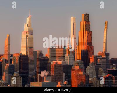 Vue aérienne de l'horizon de la ville enflammée par la lueur chaude du soleil couchant, mettant en évidence le Chrysler Building et les gratte-ciel modernes, New York, New York Banque D'Images