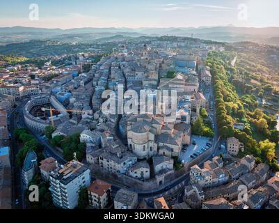 Vue aérienne des bâtiments anciens avec des toits en terre cuite descendant en cascade le long de la colline vers la route circulaire, Macerata, Italie. Banque D'Images
