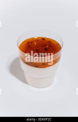 Tasse à dessert panna cotta avec sauce aux fruits de la passion sur fond blanc Banque D'Images