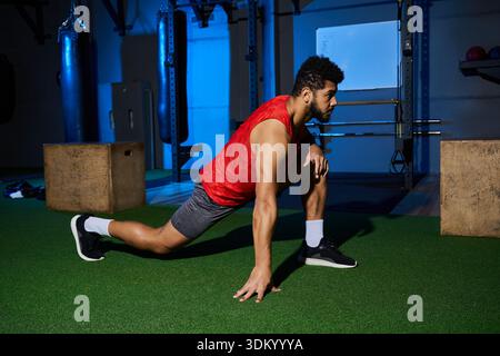 Un jeune sportif afro-américain dévoué s'étire pour se préparer à un entraînement intense au gymnase. Banque D'Images