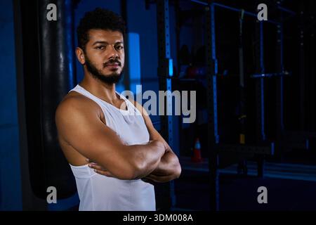 Un jeune homme noir se tient confiant dans le gymnase, concentré et prêt pour son entraînement. Banque D'Images
