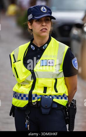 Une femme officier de la police locale italienne se tient en service portant un gilet haute visibilité jaune et un uniforme bleu marine officiel Banque D'Images