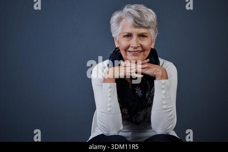 Portrait, femme heureuse et âgée en studio, vêtements décontractés et expression positive pour le bien-être de la retraite. Sourire, se détendre ou personne senior avec l'hiver Banque D'Images