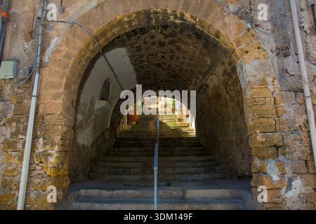 Une arche médiévale historique en pierre à Monreale, Sicile, Italie. Un passage du XIVe au XVIe siècle mène à une route plus élevée via un ensemble de marches bien usées. Banque D'Images