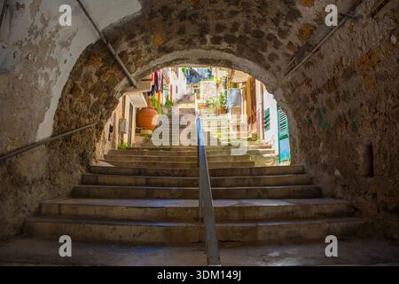Une arche médiévale historique en pierre à Monreale, Sicile, Italie. Un passage du XIVe au XVIe siècle mène à une route plus élevée via un ensemble de marches bien usées. Banque D'Images