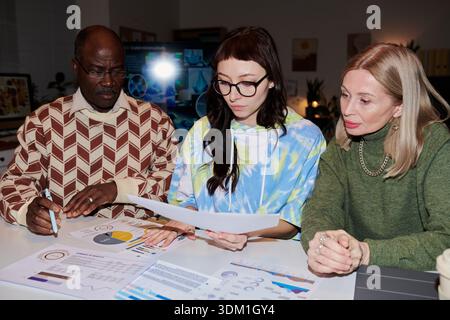 Homme noir senior et deux femmes analysant des documents commerciaux Banque D'Images