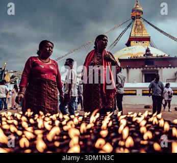 Katmandou, Népal - 27 août 2022 : vue de la flèche dorée de Boudhanath Stupa sous un ciel orageux, alors que les dévots vêtus d'une tenue rouge éclatante se rassemblent au milieu de la guerre Banque D'Images