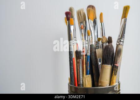 Une collection de divers pinceaux est montrée debout sur un fond clair. Ces pinceaux sont utilisés pour la peinture et l'activité artistique Banque D'Images