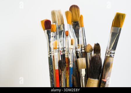 Une collection de divers pinceaux est montrée debout sur un fond clair. Ces pinceaux sont utilisés à des fins de peinture et artistiques. Banque D'Images