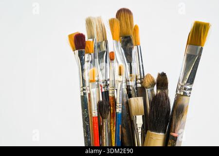 Une collection de divers pinceaux est montrée debout sur un fond clair. Ces pinceaux sont utilisés pour la peinture et l'activité artistique Banque D'Images