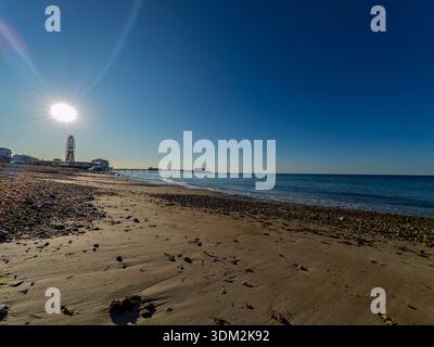 Front de mer ensoleillé de Worthing avec grande roue et jetée sur la plage de galets et calme de la Manche, ciel bleu au-dessus de vous. Banque D'Images