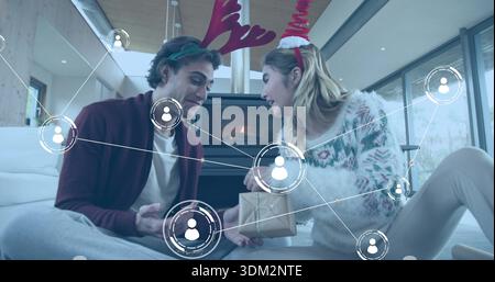 Échange de cadeau emballé, deux femmes assis sur un tapis dans le salon dans des bandeaux en bois et des chandails Banque D'Images