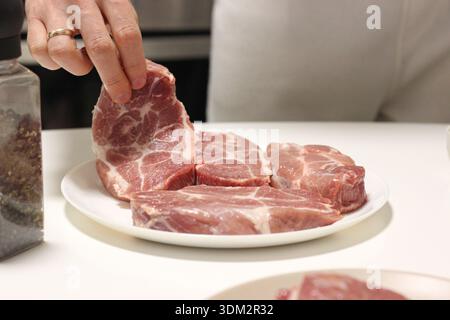 Vue rapprochée des steaks de porc cru frais disposés sur l'assiette Banque D'Images