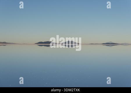 Salar de Uyuni, la vaste saline de Bolivie, devient un miroir après la pluie, reflétant le ciel et les montagnes, créant un paysage surréaliste de blanc sans fin. Banque D'Images
