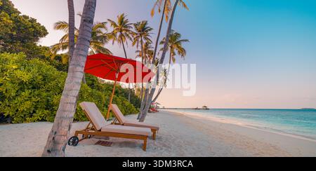 Plage panoramique tranquille au coucher du soleil, chaises longues romantiques et parasol sous les palmiers, vue imprenable sur l'océan turquoise, île tropicale de rêve Banque D'Images