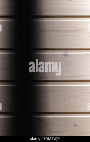 Les planches de bois lisses forment une texture murale horizontale, baignée d'une lumière douce qui crée une ombre verticale spectaculaire. Un fond polyvalent pour le design, Banque D'Images