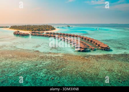 Vue aérienne immersive coucher de soleil Maldives bungalows eau paisible océan tropical paysage de vacances turquoise lagon Resort de luxe Banque D'Images