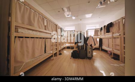 Intérieur dortoir de l'auberge avec lits superposés vides, valises et rideaux d'intimité Banque D'Images