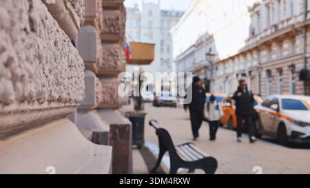 Piétons marchant sur le trottoir à Moscou avec des taxis stationnés et une façade de bâtiment ornée Banque D'Images