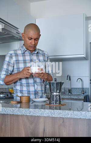 Homme tenant une tasse de café avec un pot de moka sur le comptoir Banque D'Images