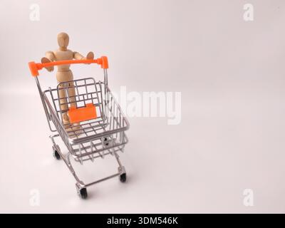 Mannequin d'artiste en bois poussant un chariot miniature en métal. Banque D'Images