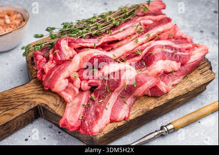 Lanières de viande de côtes courtes crues de qualité supérieure assaisonnées de sel et de thym, présentées sur une planche de bois Banque D'Images