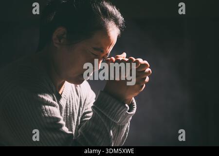 La femme a serré ses mains dans la prière, remplie de foi et d'espérance, croyant en Jésus Christ, et cherchant la sainte présence de Dieu à travers ses prières Banque D'Images