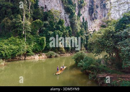 Vivez un voyage tranquille en radeau de bambou le long des rivières paisibles de Khao Sok, entouré par d'imposantes falaises et une jungle dense à Surat Thani, Thaila Banque D'Images
