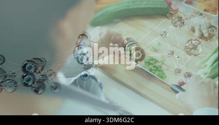 Coupe senior Indien dans des manches légères tranchant le concombre sur la planche à découper de cuisine avec réseau de couteaux Banque D'Images