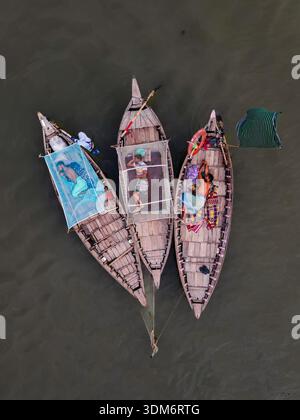 Dhaka, Bangladesh - 31 août 2024 : vue aérienne de trois bateaux rustiques en bois regroupés sur les eaux obscures et ondulantes, chacun transportant des couleurs vives Banque D'Images